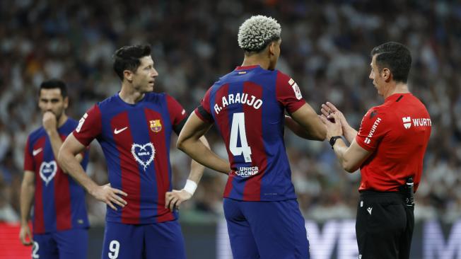 MADRID, 21/04/2024.- El colegiado César Soto Grado (d) conversa con el defensa uruguayo del FC Barcelona Ronald Araújo (c) durante el partido de la jornada 32 de LaLiga EA Sports entre Real Madrid y FC Barcelona, este domingo en el estadio Santiago Bernabéu de Madrid. EFE/ Juanjo Martín