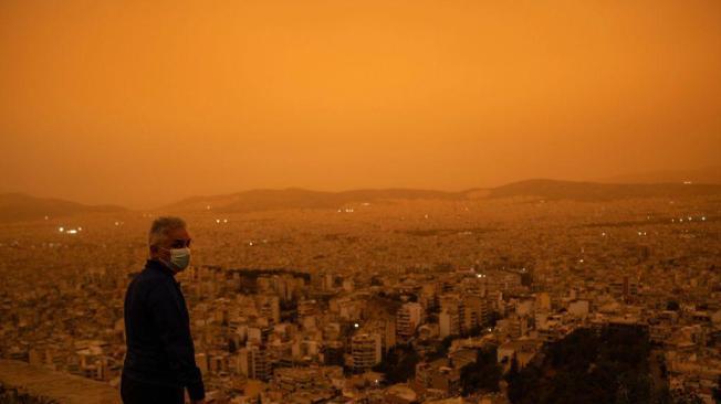 Un hombre con una mascarilla mira hacia la ciudad de Atenas desde la colina Tourkovounia.