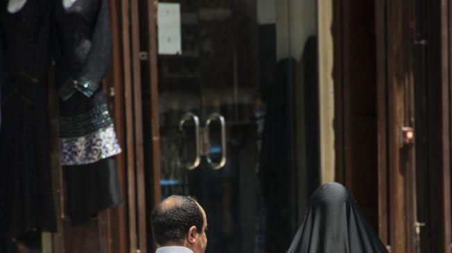 Una pareja saudita camina por las calles de Al Balad, vestidos con la vestimenta tradicional.
