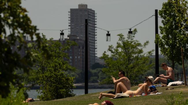 Personas sentadas en la hierba junto al río Hudson durante una ola de calor esta semana.
