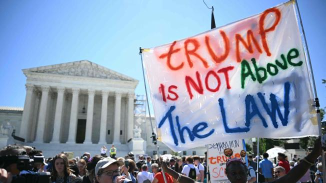 La gente sostiene carteles contra Trump frente a la Corte Suprema de Estados Unidos el 1 de julio de 2024, en Washington, DC.