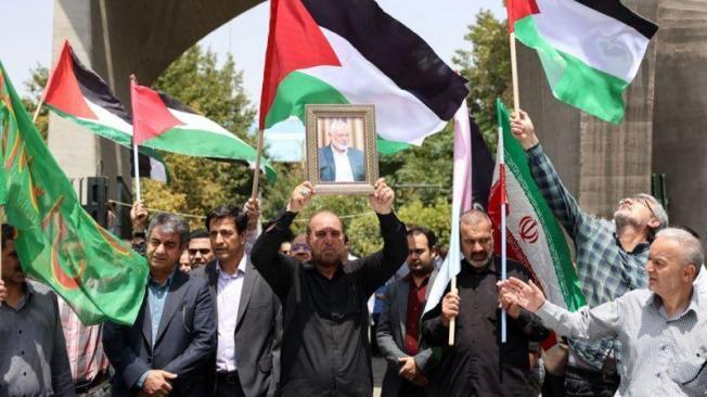 Iraníes con banderas palestinas e iraníes llevan el retrato de Ismail Haniyeh en Teherán