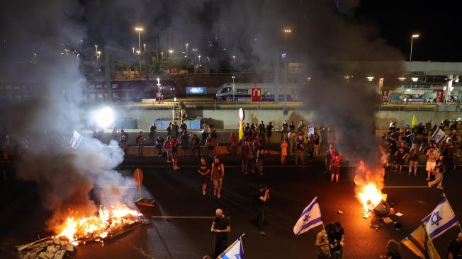 Manifestantes en apoyo a las familias de los rehenes israelíes retenidos por Hamás en Gaza encienden hogueras mientras bloquean la carretera principal de Ayalon durante una manifestación de protesta en Tel Aviv, Israel.