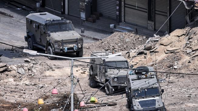 Vehículos blindados del ejército israelí avanzan por un tramo excavado de una carretera en el centro de Yenín, en Cisjordania.