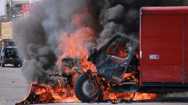 A truck on fire is seen on the streets of Culiacan, Sinaloa State, Mexico, on September 11, 2024. Elements of Mexico's National Guard were deployed in the state of Sinaloa, in the northwest of the country, amid an escalation of violence that authorities attribute to internal struggles within the Sinaloa cartel following the capture of its leader, Ismael "Mayo" Zambada. (Photo by Ivan MEDINA / AFP)