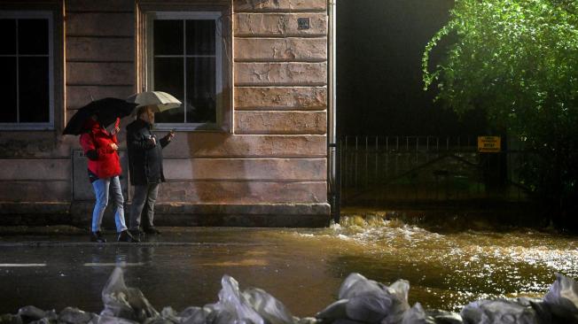 Los residentes locales toman fotografías con sus teléfonos móviles mientras el agua del río Biala llega al centro de la ciudad de Glucholazy, en el sur de Polonia, el 14 de septiembre de 2024.