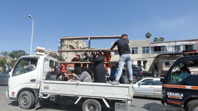 A Syrian family sit with their belongings in the back of a truck as they wait in a traffic jam in the southern Lebanese city of Sidon on September 23, 2024. The Israeli military on September 23 told people in Lebanon to move away from Hezbollah targets and vowed to carry out more "extensive and precise" strikes against the Iran-backed group. (Photo by Mahmoud ZAYYAT / AFP)