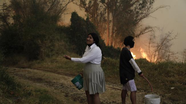 -FOTODELDÍA- AME2225. QUITO (ECUADOR), 24/09/2024.- Personas intentan apagar un incendio con baldes de agua este martes, en Quito (Ecuador). Varios incendios forestales en los alrededores de Quito, han teñido con una espesa capa de humo a la ciudad, por lo que la autoridades han lanzado una alerta por la mala calidad del aire, sobre todo en el norte de la ciudad. EFE/ Santiago Fernández