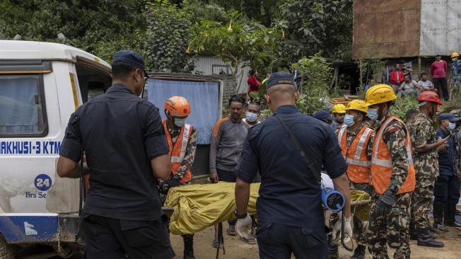 Miembros de un equipo de rescate recogen los cadáveres de los pasajeros de los autobuses enterrados en un deslizamiento de tierra en Jhyaple Khola, distrito de Dadhing, Nepal.