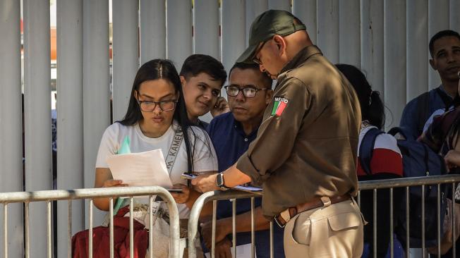 Personal de migración revisa documentos a migrantes, este miércoles en la ciudad de Tijuana (México). La organización binacional Al Otro Lado acusó a agentes de la Oficina de Aduanas y Protección Fronteriza de Estados Unidos de rechazar a migrantes en la frontera con la mexicana Tijuana aunque ya tengan sus citas de asilo programadas con la aplicación 'CBP One'. EFE/ Joebeth Terríquez