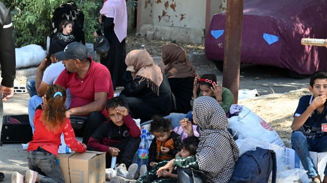 Sirios y libaneses desplazados se sientan a descansar tras entrar en Siria desde Líbano.