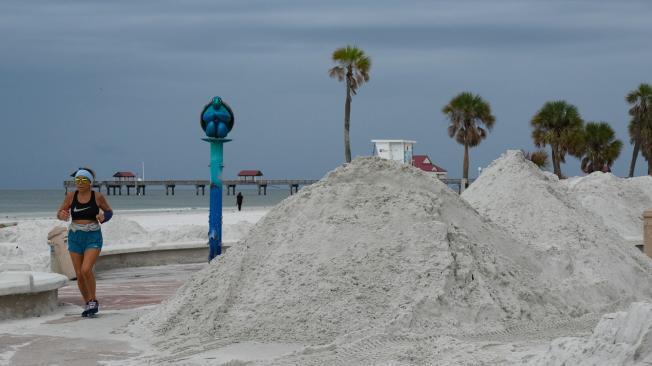 Una mujer corre a lo largo de montones de arena despejados de la calle como resultado del huracán Helene en Clearwater, Florida, antes de la llegada prevista del huracán Milton a mitad de semana, el 6 de octubre de 2024.