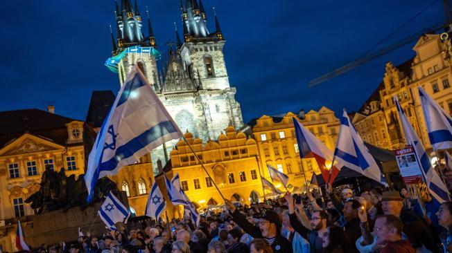 Un grupo de personas ondean banderas israelíes mientras asisten a una concentración en Praga con motivo del aniversario del ataque dirigido por Hamás contra Israel.