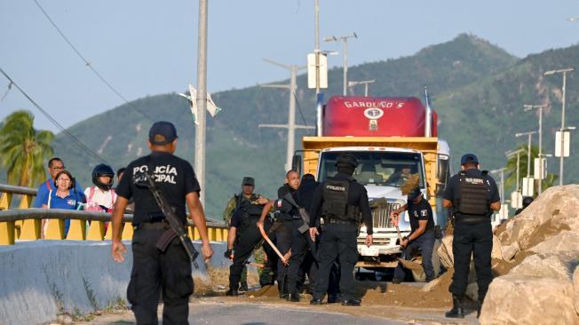 La policía municipal mueve los restos de un camión quemado y piedras que bloquean la carretera en el municipio de Coyuca de Benítez, estado de Guerrero, México, el 24 de octubre de 2024