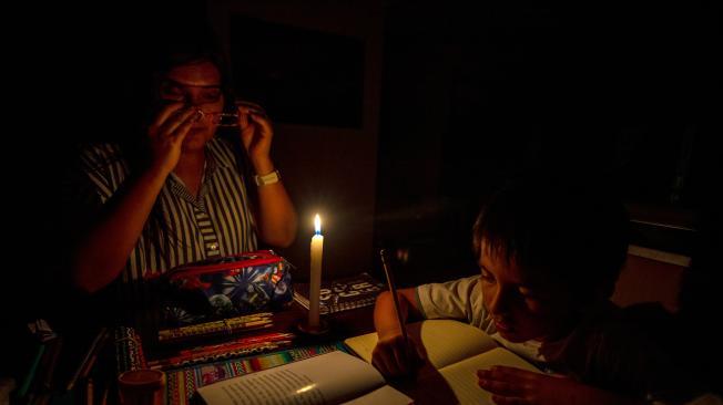 Una madre y su hijo estudian a la luz de la vela este viernes en Quito (Ecuador). Ecuador inicia tres días de apagones programados de hasta catorce horas al día, producto de un agravamiento de la crisis energética generada, principalmente, por una histórica sequía en las zonas de sus principales centrales hidroeléctricas. EFE/José Jácome