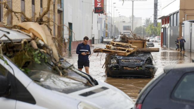 Varias personas transitan por el polígono industrial de Sedaví anegado a causa de las lluvias torrenciales de las últimas horas.