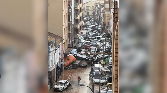 Ciudadanos viendo callejón de carros volcados tras La Dana, Valencia