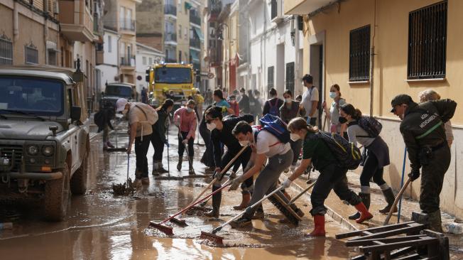 Varias personas trabajan para limpiar el barro y los escombros de una calle de Aldaia, en la región de Valencia.