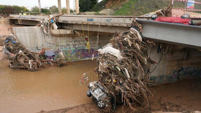 Restos de coches y escombros, arrastrados por el río crecido, se acumulan en un puente en Catarroja, Valencia.