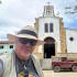 El médico Diego Rosselli frente a la iglesia de Santa Helena del Opón (Santander). Al fondo uno de sus Land Rover.