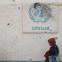 Una mujer palestina pasa junto a un muro dañado que lleva el logotipo de la UNRWA en un campamento para desplazados internos en Rafah, en el sur de la Franja de Gaza.