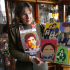 Rosalba Campos Guevara sostiene un bordado y varios cuadros en los que se recuerda el caso del Colectivo 82.