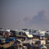Un campamento de palestinos desplazados internos en la frontera de Gaza con Egipto, mientras se eleva el humo de un ataque aéreo israelí