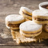 Traditional Argentinian alfajores with dulce de leche and sugar on wooden table.