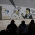 Personas esperan frente a un mural durante un apagón nacional este viernes, en Caracas (Venezuela).