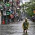 A man wearing a plastic poncho wades through flood waters on a street in Hanoi on September 11, 2024