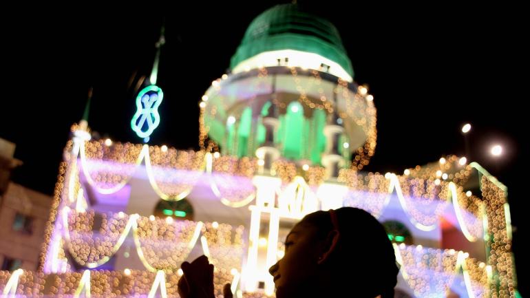 Una chica ruega junto al alumbramiento de la mezquita de Memon ('Memon Masjid'), durante la celebración de la festividad musulmana del Mawlid, el día que conmemora el nacimiento del profeta sagrado para los musulmanes, Mahoma, en Karachi, Pakistán.