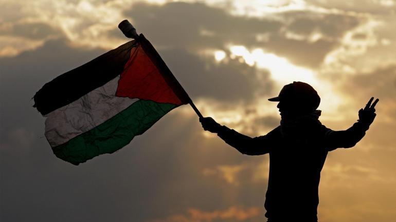Un joven palestino sostiene una bandera de Palestina, cerca de la frontera de Gaza con Israel, durante los enfrentamientos originados por el reconocimiento, por parte de los Estados Unidos, de Jerusalén como capital de Israel.