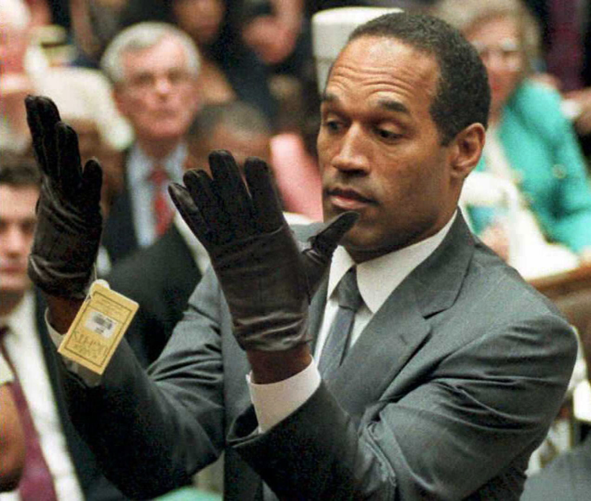 O.J. Simpson mira los guantes que se midió ante la Corte.