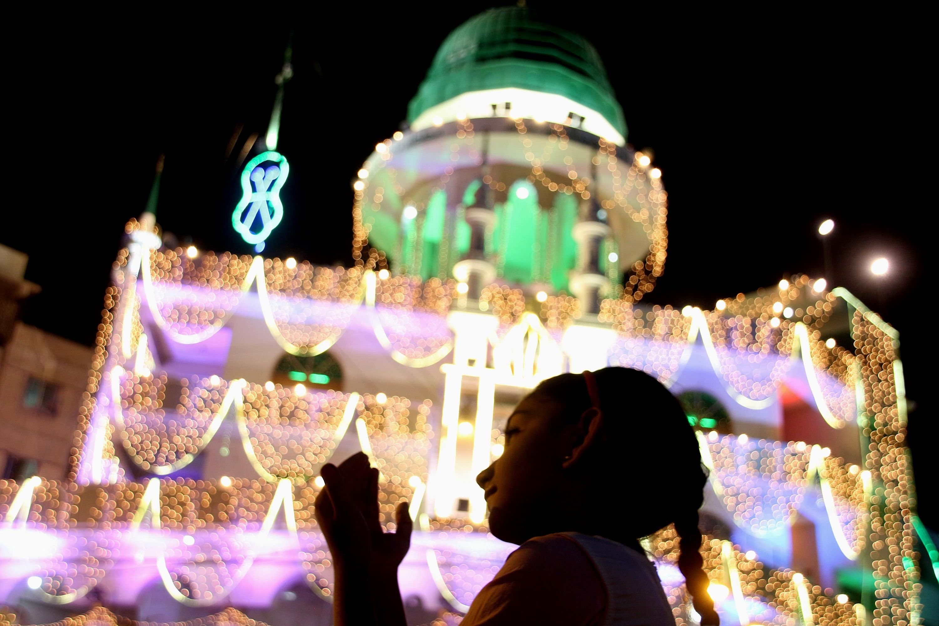 Una chica ruega junto al alumbramiento de la mezquita de Memon ('Memon Masjid'), durante la celebración de la festividad musulmana del Mawlid, el día que conmemora el nacimiento del profeta sagrado para los musulmanes, Mahoma, en Karachi, Pakistán.