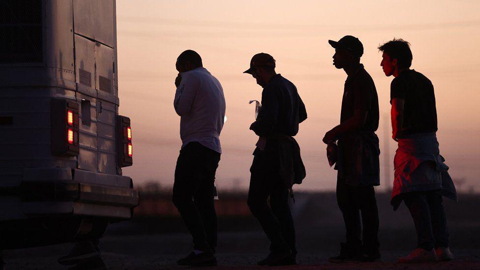 Migrantes esperando abordar un autobús en Arizona después de cruzar desde México.