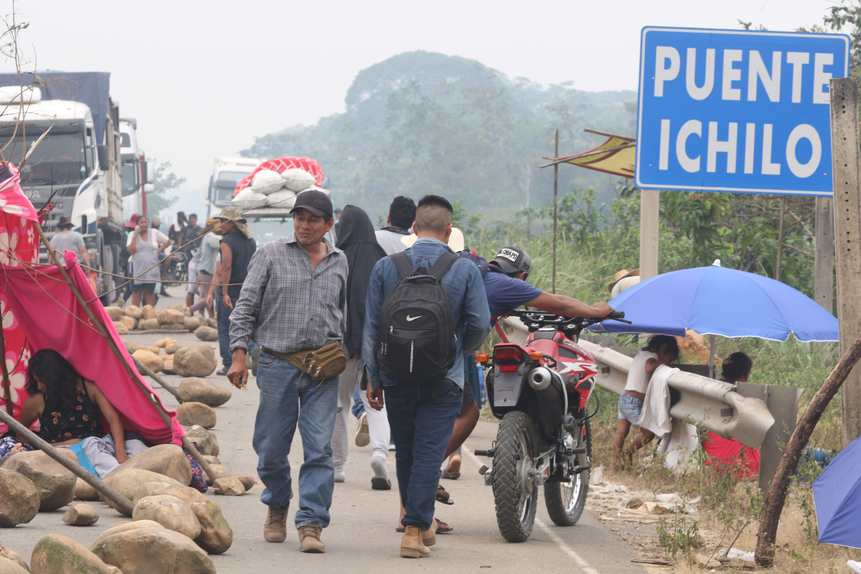 Personas caminan en una vía con escombros durante un bloqueo instalado por seguidores del expresidente Evo Morales (2006-2019) este lunes en Puente Ichilo