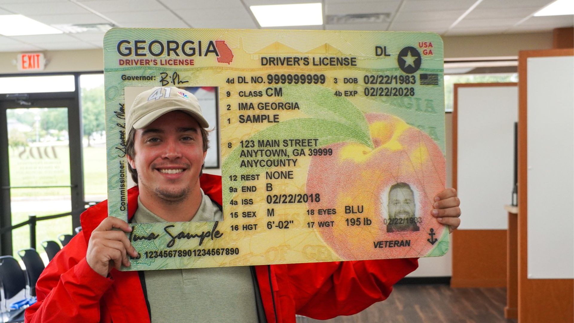 Un hombre sostiene un cartel con una licencia de conducir Real ID grande.
