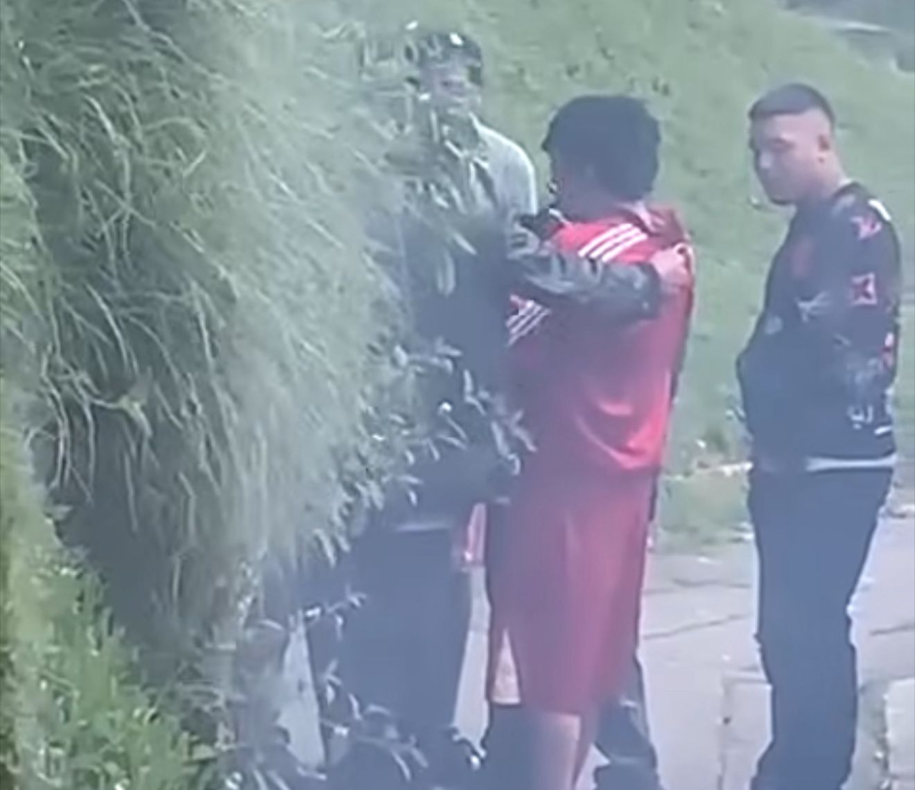 Fotograma del video que mudra A Harold Aoca, Con Pantaloneta Roja, Rodeado por curoto Hombres en Los Laches.